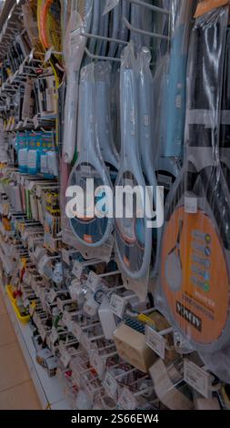 A store aisle displaying various household items, including electric fly swatters, cleaning supplies, and other tools, neatly arranged on shelves. Stock Photo