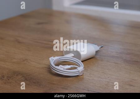 A charger for gadgets. A power adapter and cable in white color. Stock Photo