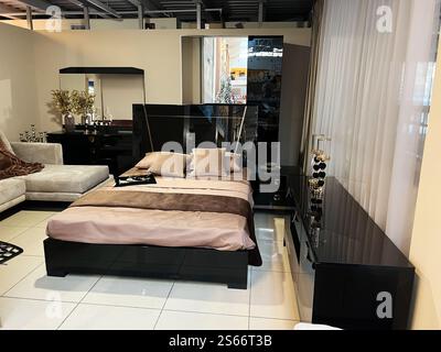 A contemporary bedroom featuring sleek black furniture, a polished bed, and tasteful decor. The setting includes modern furnishings and a cozy ambianc Stock Photo
