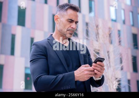 Confident businessman using smartphone outdoors, Stock Photo