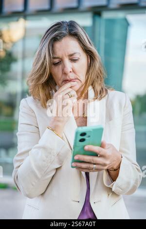 Thoughtful Woman Using Smartphone Outdoors.Vertical Stock Photo