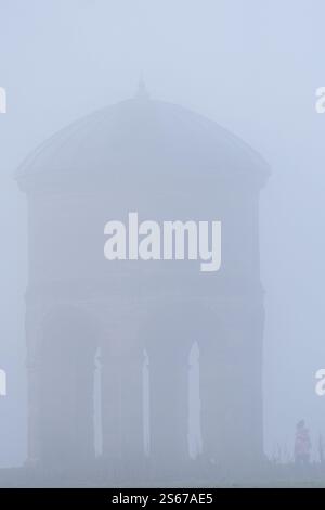 A person walks by Chesterton Windmill during heavy fog in Chesterton in Warwickshire. A yellow alert for fog has come into force, with the Met Office warning the weather could cause travel disruption including flight delays or cancellations. Picture date: Thursday January 16, 2025. Stock Photo