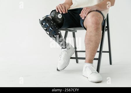 A Man with a prosthetic leg Sitting on Stool Stock Photo
