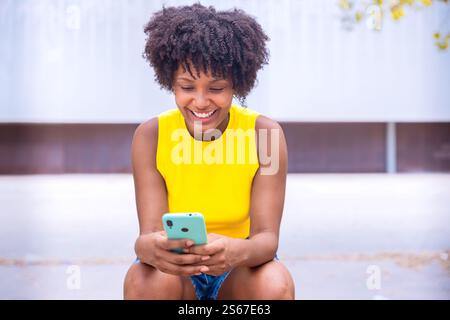Smiling african american Young Woman Holding Smartphone Outdoors Stock Photo