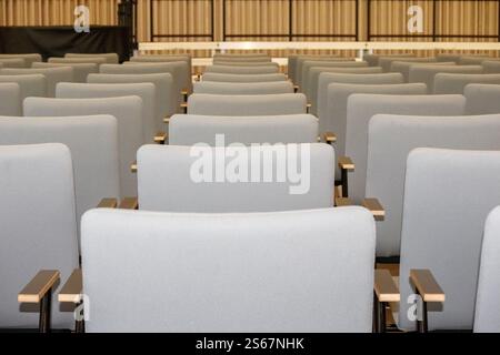Fragment of an empty conference hall or auditorium with rows of gray chairs. Stock Photo