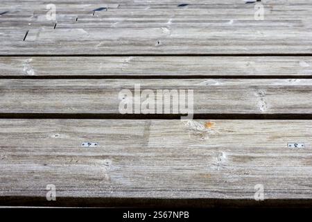 Close-up of worn wooden planks joined together to form a surface with visible gaps between the planks. Stock Photo