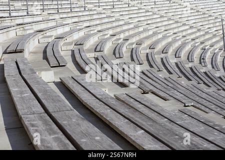 An empty, wooden-seated amphitheater with concrete structures. Stock Photo