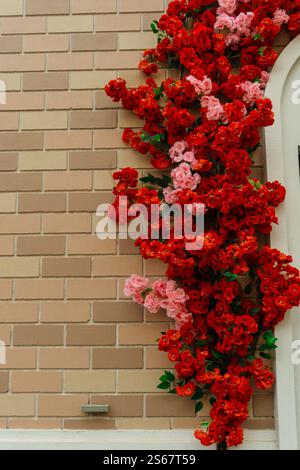 decorating the store entrance with red flowers. artificial flowers on exterior wall of the building Stock Photo
