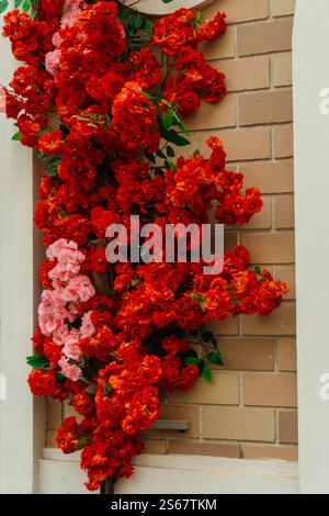 decorating the store entrance with red flowers. artificial flowers on exterior wall of the building Stock Photo