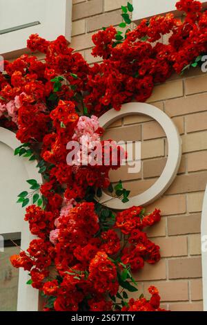 decorating the store entrance with red flowers. artificial flowers on exterior wall of the building Stock Photo