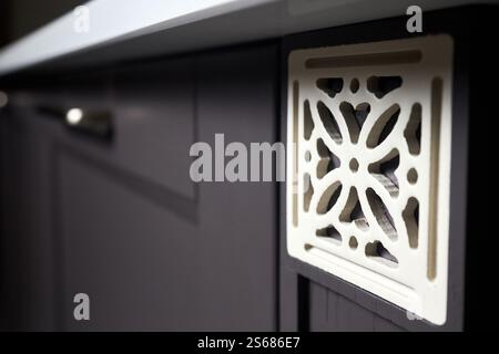 Close up square shape lattice element of brightly lit wooden painted cabinet door milling carved with simple floral pattern ornamental, selective focu Stock Photo