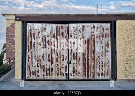 Rusty gates on trash dumpster enclosure closed commercial building exterior. Stock Photo