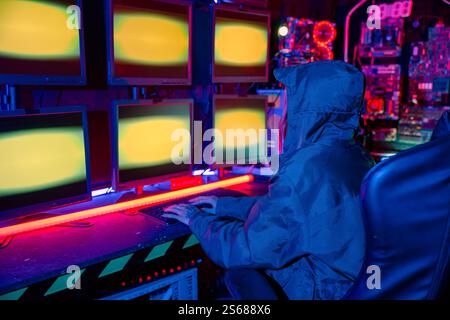 Woman hacker wear hood sit front computer typing on keyboard hacking servers in neon light, Gamer Stock Photo