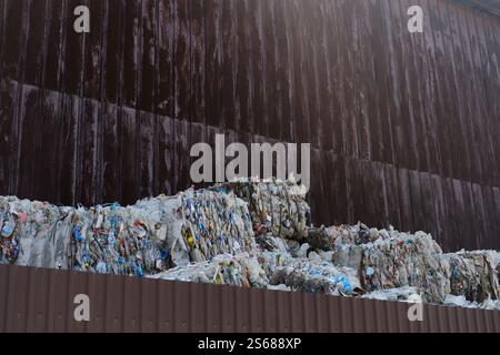 Plastic bottles compressed into cubes and ready for recycling against the background of a brown wall at a Waste processing plant. Stock Photo