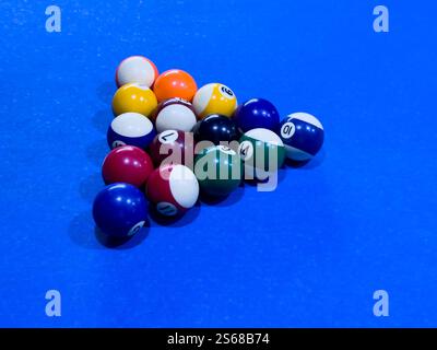 Colorful billiard balls arranged on a blue pool table before a game Stock Photo