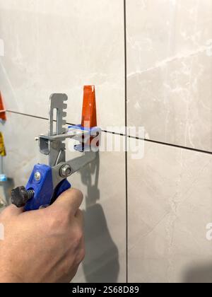 Tiling process in action with manual tile leveling tool being used Stock Photo
