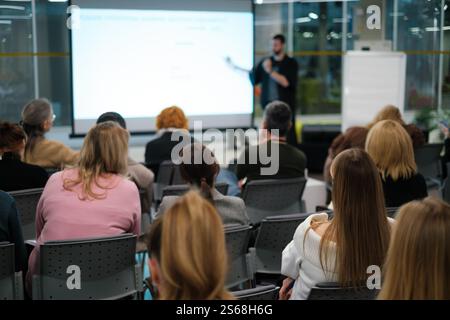 Business presentation with diverse audience in office setting, focusing on learning and networking within a corporate environment. Stock Photo