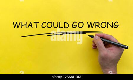 Hand writing What Could Go Wrong text on yellow cover board Stock Photo
