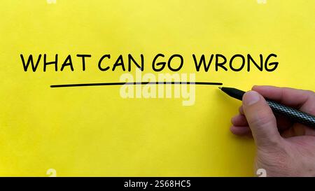 Hand writing What Can Go Wrong text on yellow cover board Stock Photo
