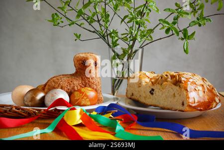 Easter still life containing a small lamb cake, painted eggs, traditional Czech Easter sweet cake called "mazanec", an Easter whip and green twigs Stock Photo