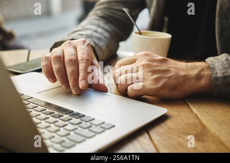 A Caucasian male works on a computer in a street city cafe. Remote work concept. Stock Photo
