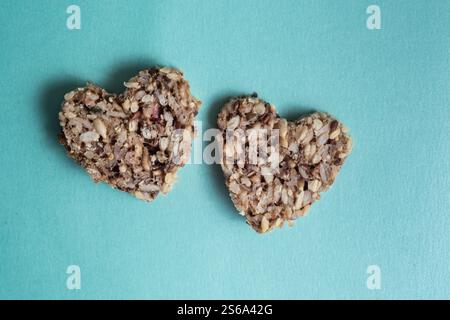 Healthy vegan heart-shaped bread made from various seeds on a blue background. Valentine's day concept. Valentine's day concept. Copy space Stock Photo