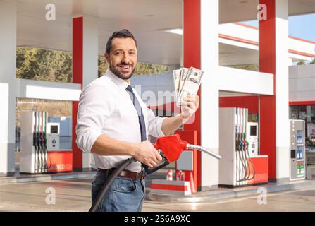 Smiling  man holding a refuel petrol gun and money at a gas station Stock Photo