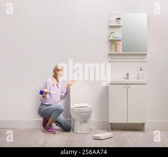 Woman in a bathroom fixing a broken water tank Stock Photo