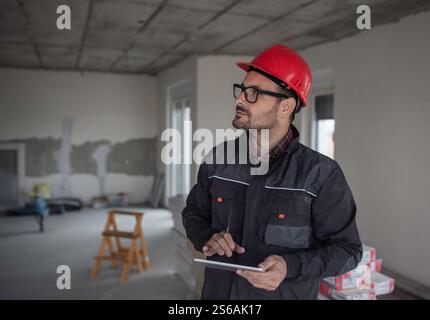 Portrait of construction engineer using tablet in residental building under construction during interior works Stock Photo