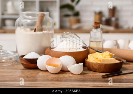 Flour in jar with eggs, butter and rolling pin for preparing dough on kitchen counter Stock Photo