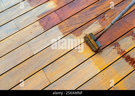 Close-up of a wooden deck being stained with a brush for protection and maintenance during a home improvement project in bright sunlight Stock Photo