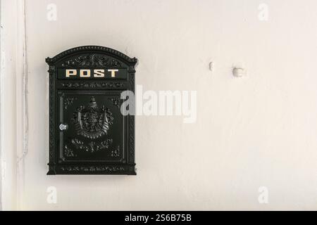 Black metal mailbox on white wall Stock Photo