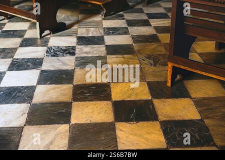 Old wood church pews on marble floor with black and white checkered pattern Stock Photo