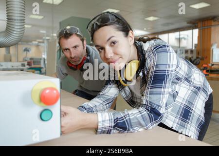 male worker watching female apprentice operating machinery Stock Photo