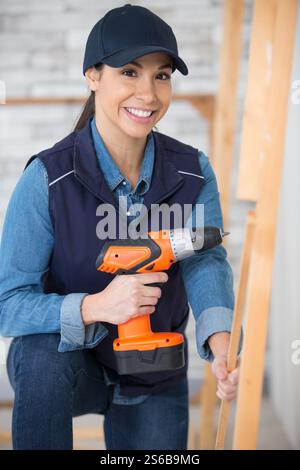 female worker using drill on wooden pieces Stock Photo