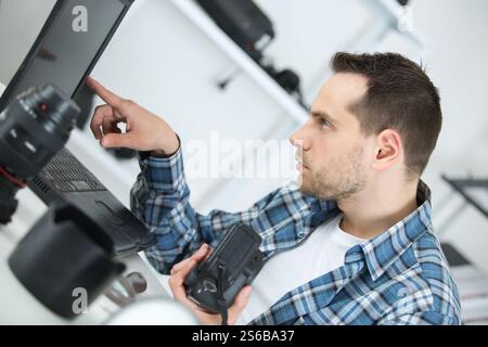 camera repairman looking at laptop Stock Photo
