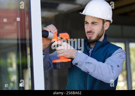 workman using cordless drill on sliding door Stock Photo