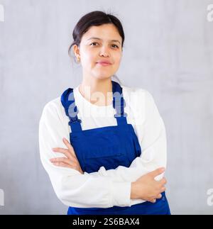 A cleaning lady in a blue uniform washes a tiled floor with a mop ...