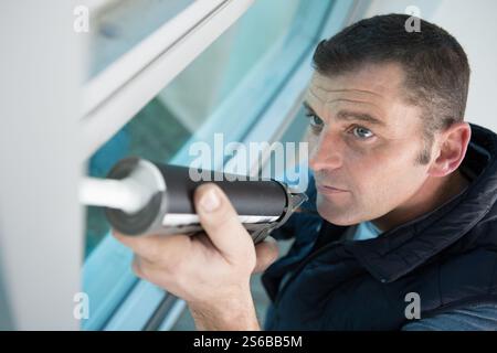 construction worker using caulk gun on window Stock Photo