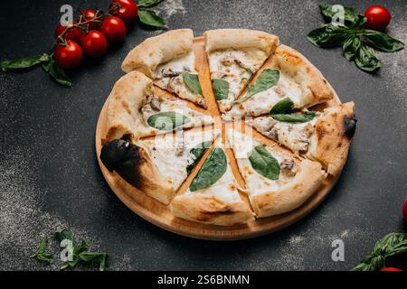 Freshly baked white pizza slices with creamy mushrooms and spinach, served on a wooden plate Stock Photo