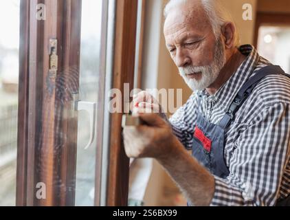 Portrait of mature craftsman fixing window handle inside house Stock Photo