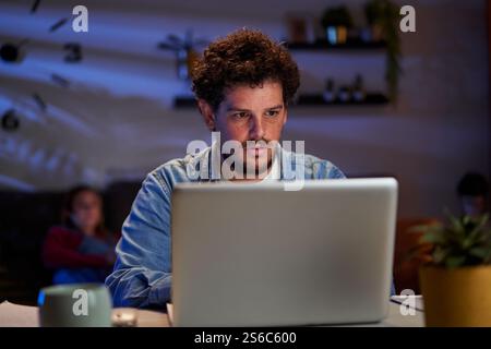 Focused freelancer working late on laptop at home office. Stock Photo