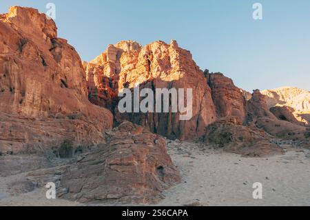 A rocky mountain range with a clear blue sky. The sun is shining brightly on the rocks, creating a warm and inviting atmosphere Stock Photo
