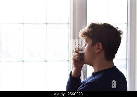 Young man using puffer inhaler to control his asthma Stock Photo