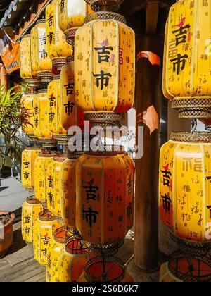 Dali, China - November 19, 2024 : A vibrant display of yellow, octagonal lanterns hangs outdoors.  Each lantern features intricate gold Chinese charac Stock Photo