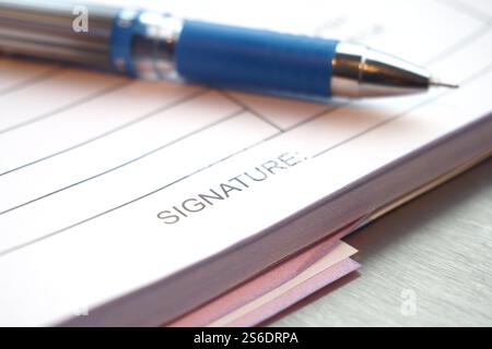 Closeup view of a Blue Pen resting on the Signature Line of Important Documents Stock Photo