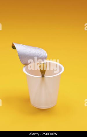An empty clean yogurt cup with spoon on an orange background Stock Photo