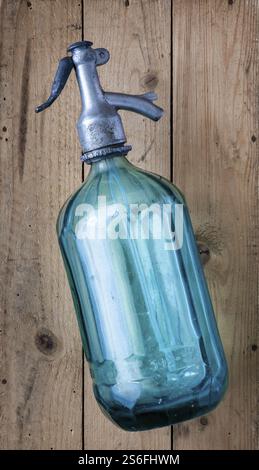 An old vintage turquoise soda glass bottle on a wooden table Stock Photo