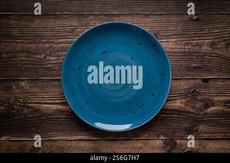 Top view of empty ceramic blue plate on wooden background Stock Photo