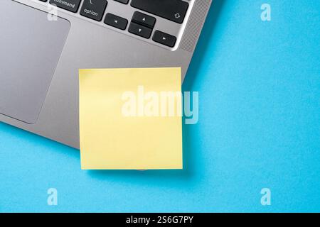 Note paper stuck to the corner of the laptop on the blue desk Stock Photo